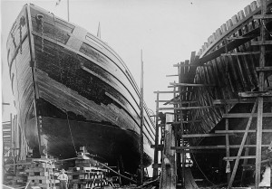 Wooden ships being constructed on the ways. Note the wooden frame of the ship on the right and the wood planking making up the hull of the ship on the left.